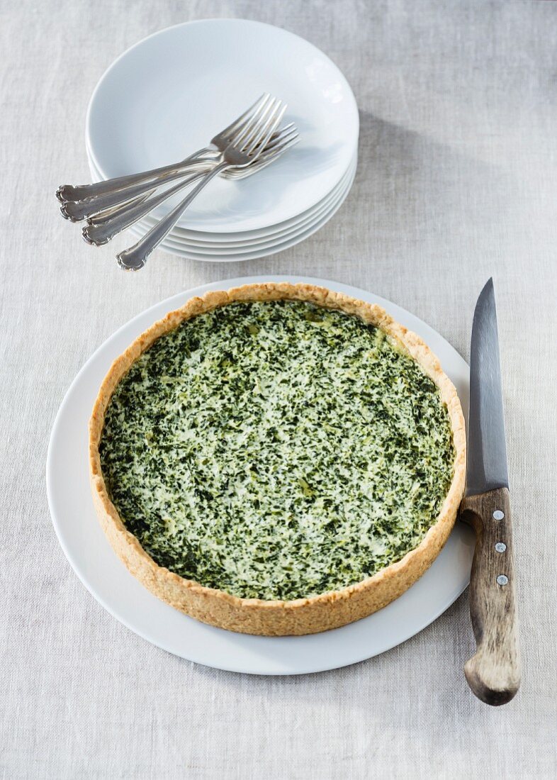 Spinach quiche on a plate with a knife