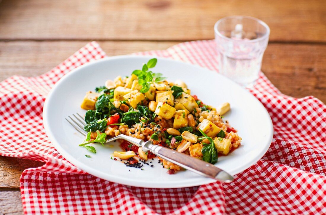 Tomato-infused barley risotto with tofu, peanuts and spinach