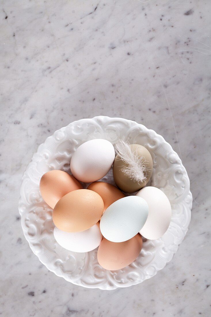 Fresh eggs on a plate with a feather (seen from above)
