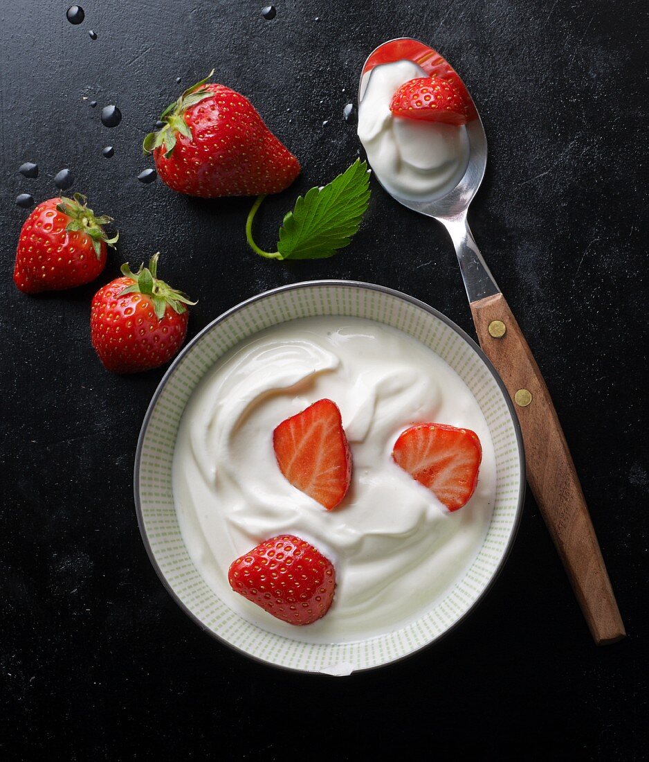 Joghurt mit frischen Erdbeeren in Schale und auf Löffel