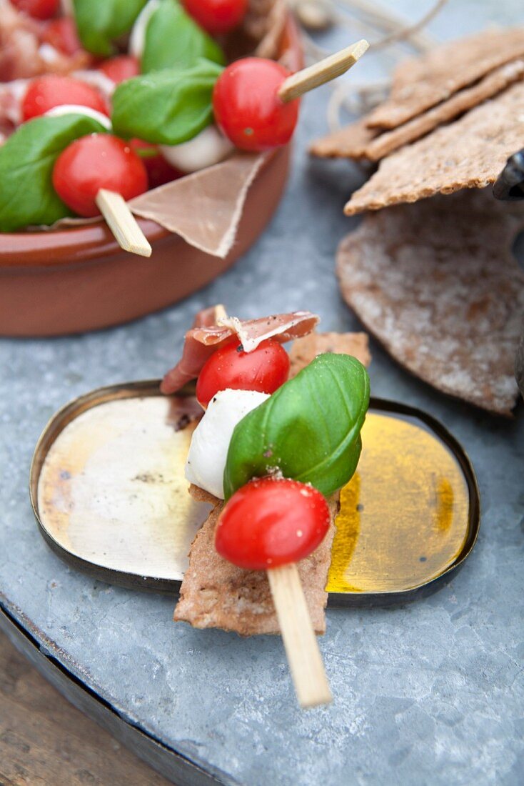Tomato and mozzarella skewers with Parma ham and basil on crispbread