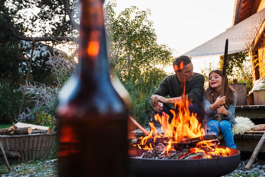 Vater und Tochter im Garten mit brennendem Feuer in einer Feuerschale