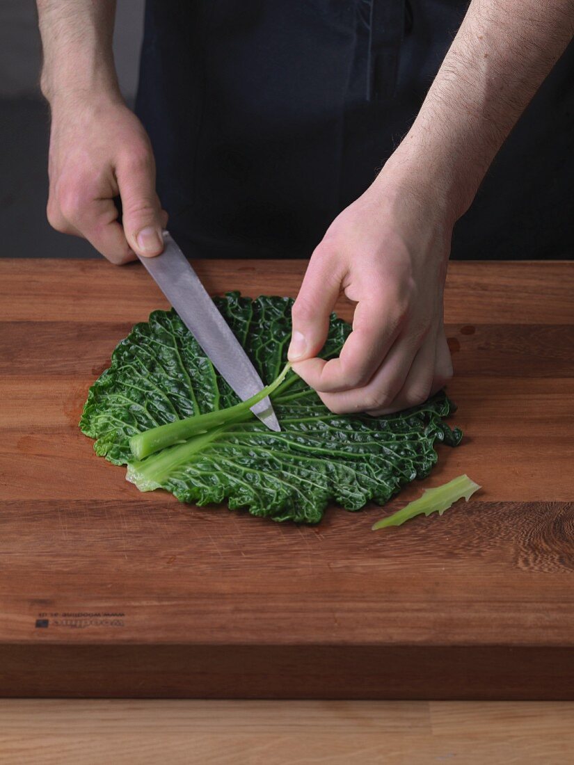 The mid-rib section being cut out of a leaf of blanched savoy cabbage