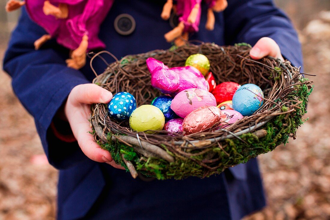 A child holding an Easter nest filled with Easter eggs