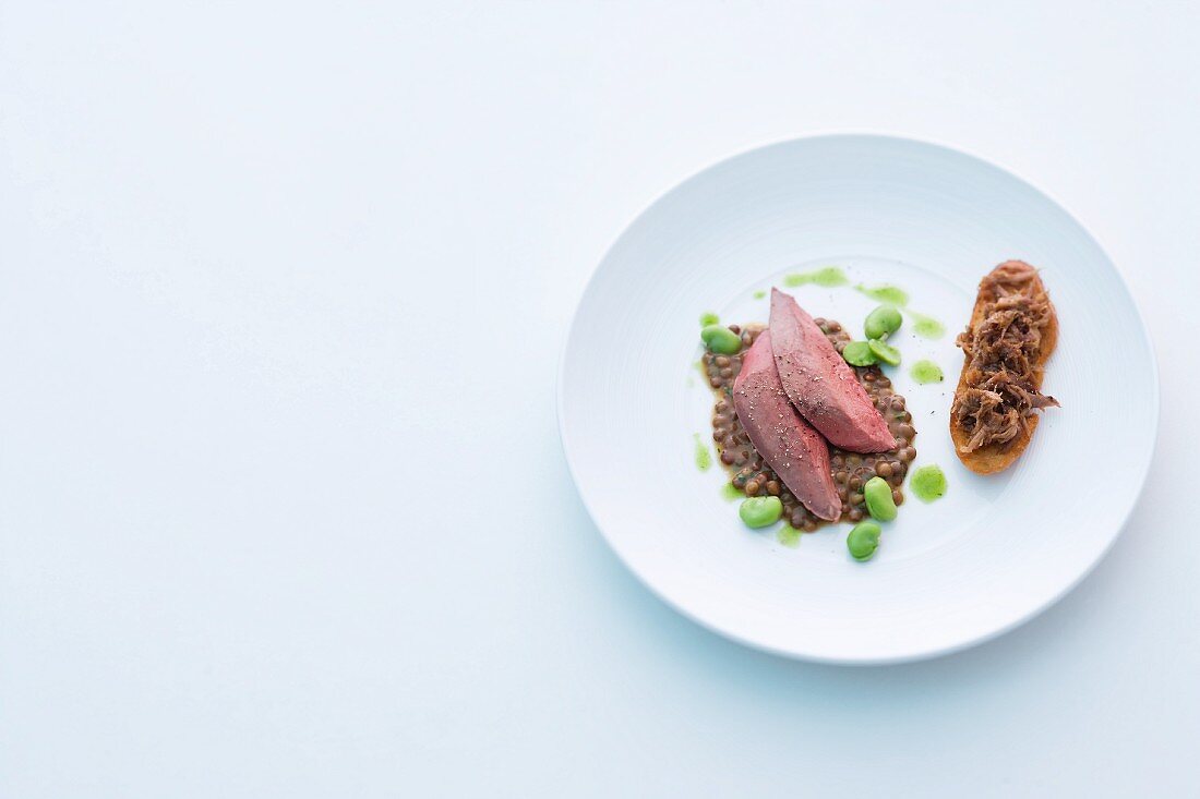 Pigeon on a bed of lentils with broad beans