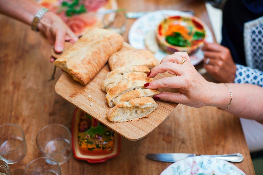 Three older women eating together: bread being served