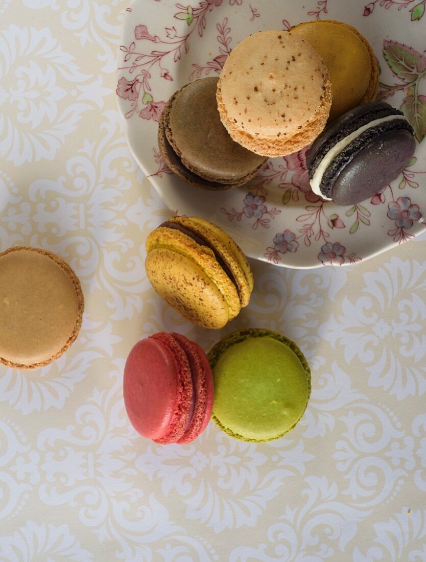 Various macaroons on a plate and on a table (seen from above)