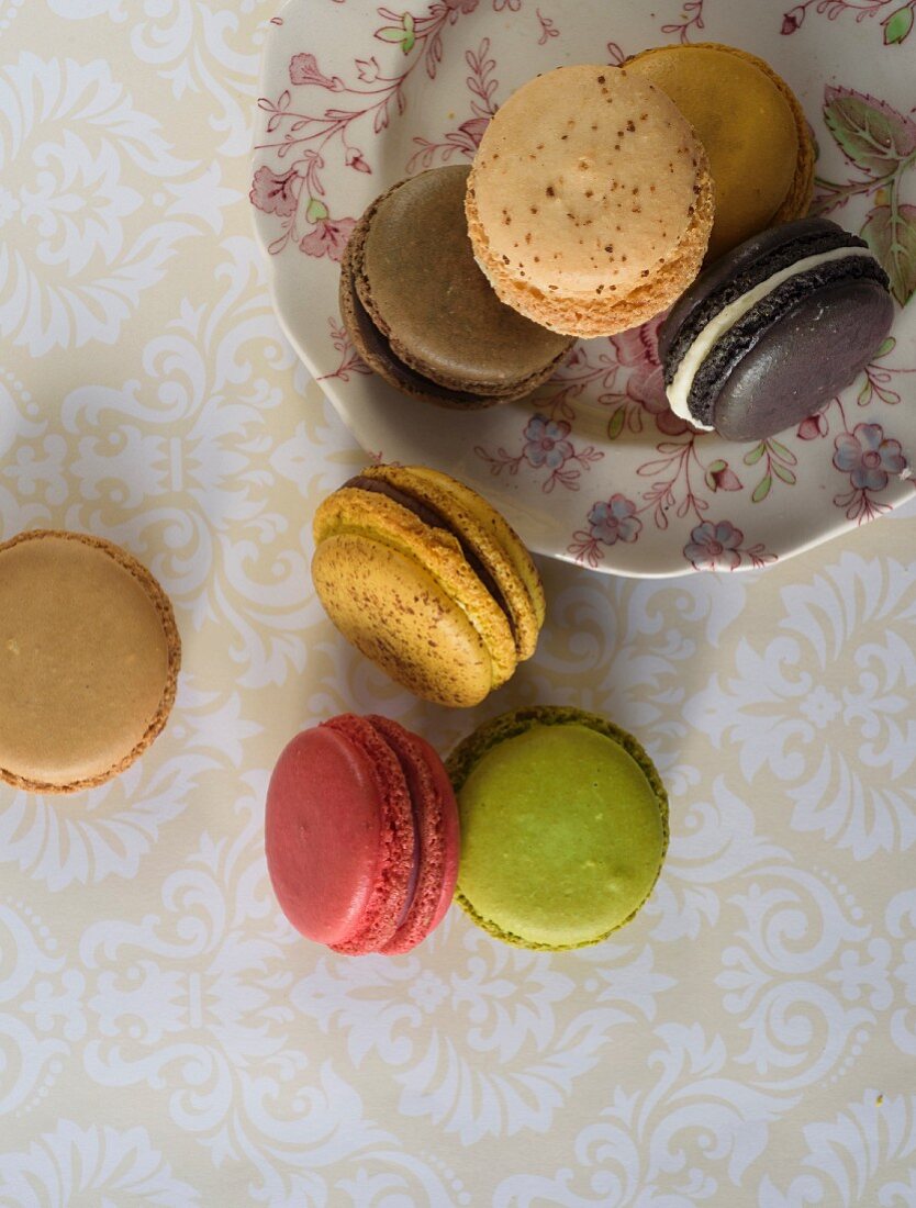 Verschiedene Macarons auf Teller und Tisch (Aufsicht)