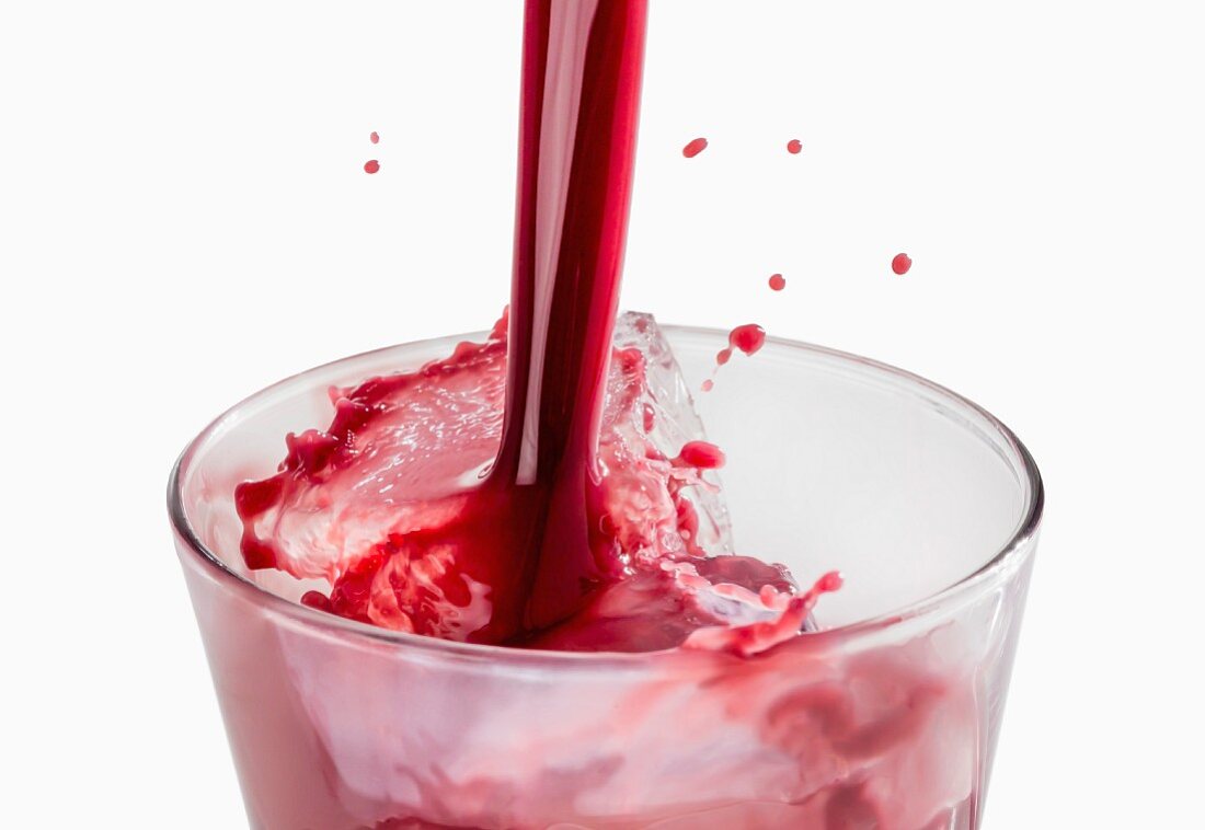Red juice being poured into a glass