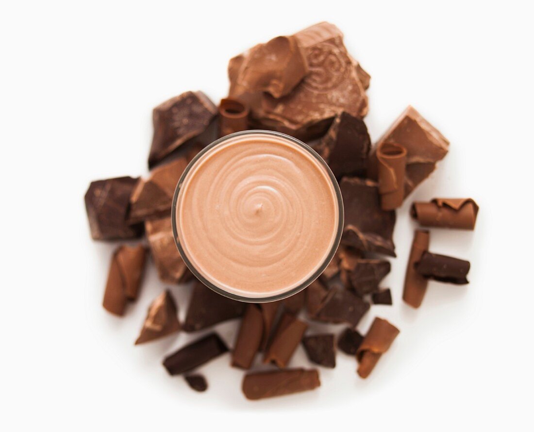 A chocolate shake surrounded by pieces of chocolate (seen from above)