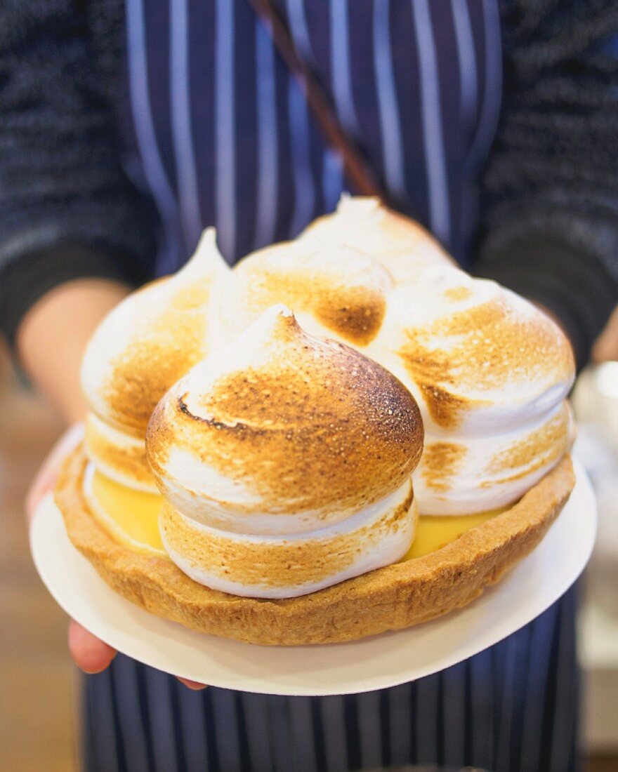 A person holding a gluten-free lemon meringue pie