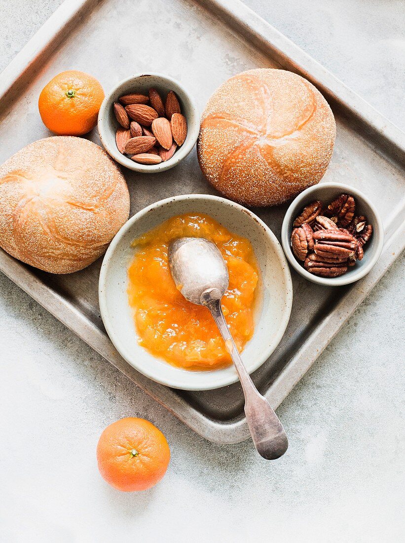 Bread rolls, jam, almonds and mandarins