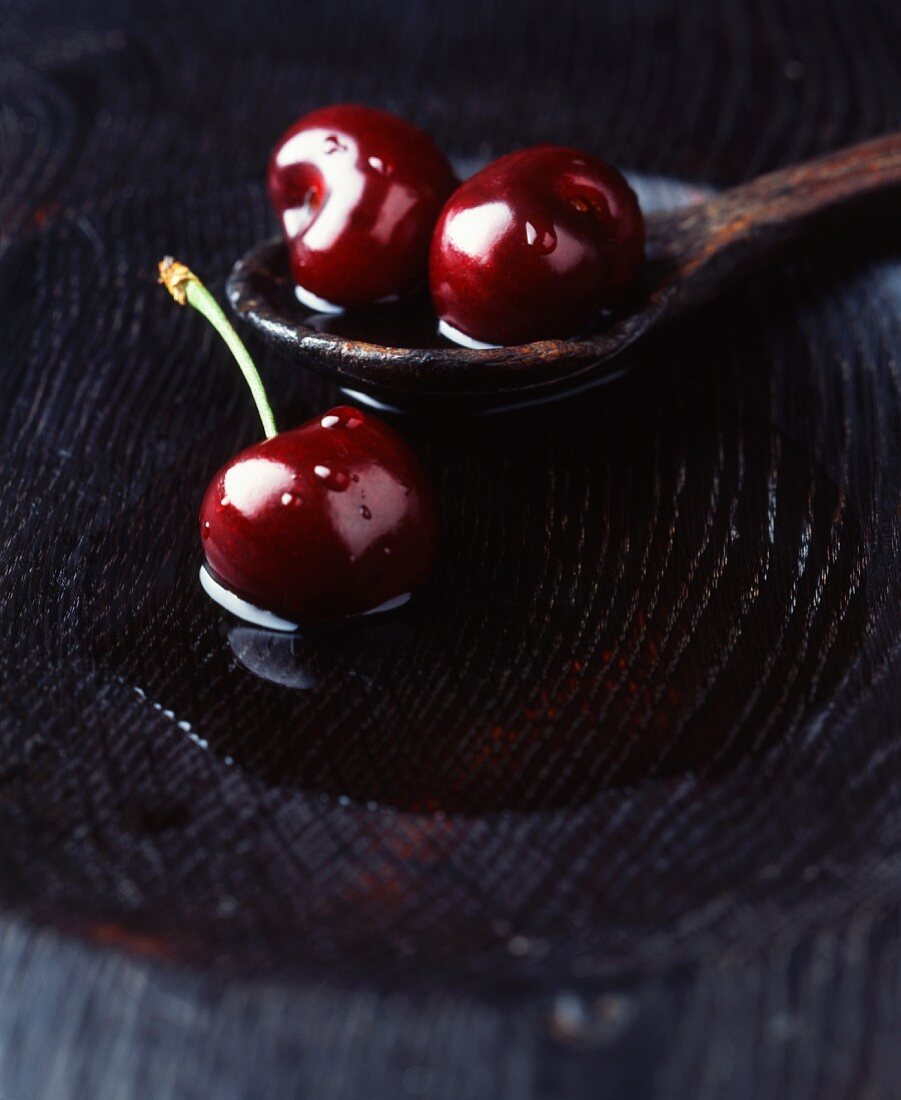 Fresh cherries on a wooden spoon in a bowl of water