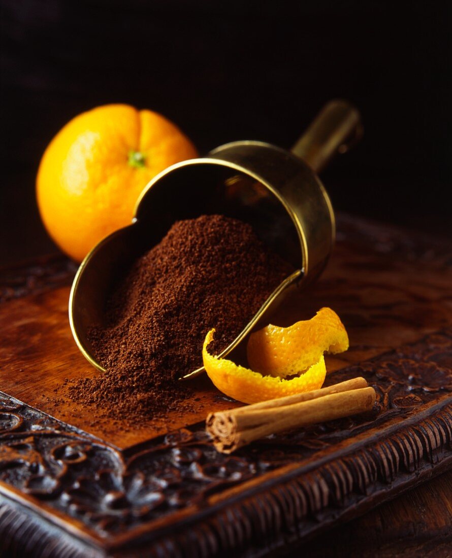 Frische Orangen und Schalen mit Zimtstange und frisch gemahlenem Kaffee in Schütte