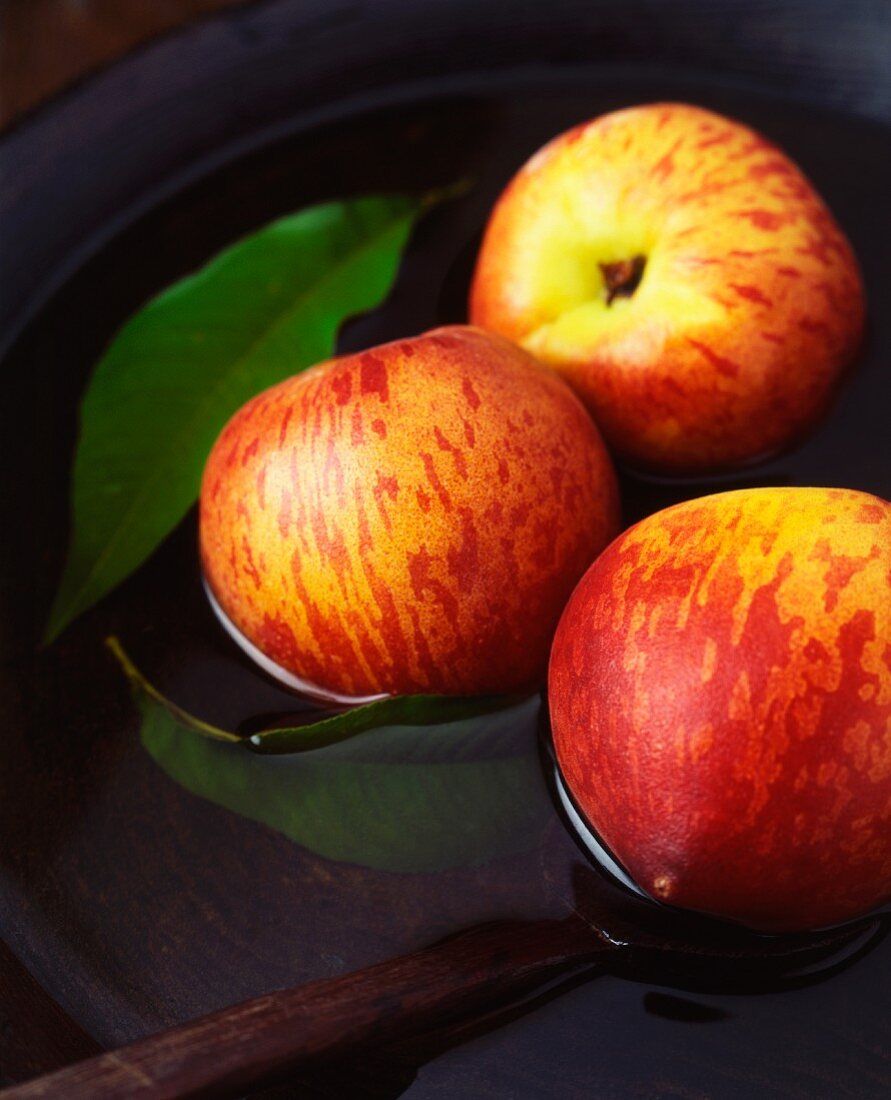 Three apples and leaves in a vintage wooden bowl of water