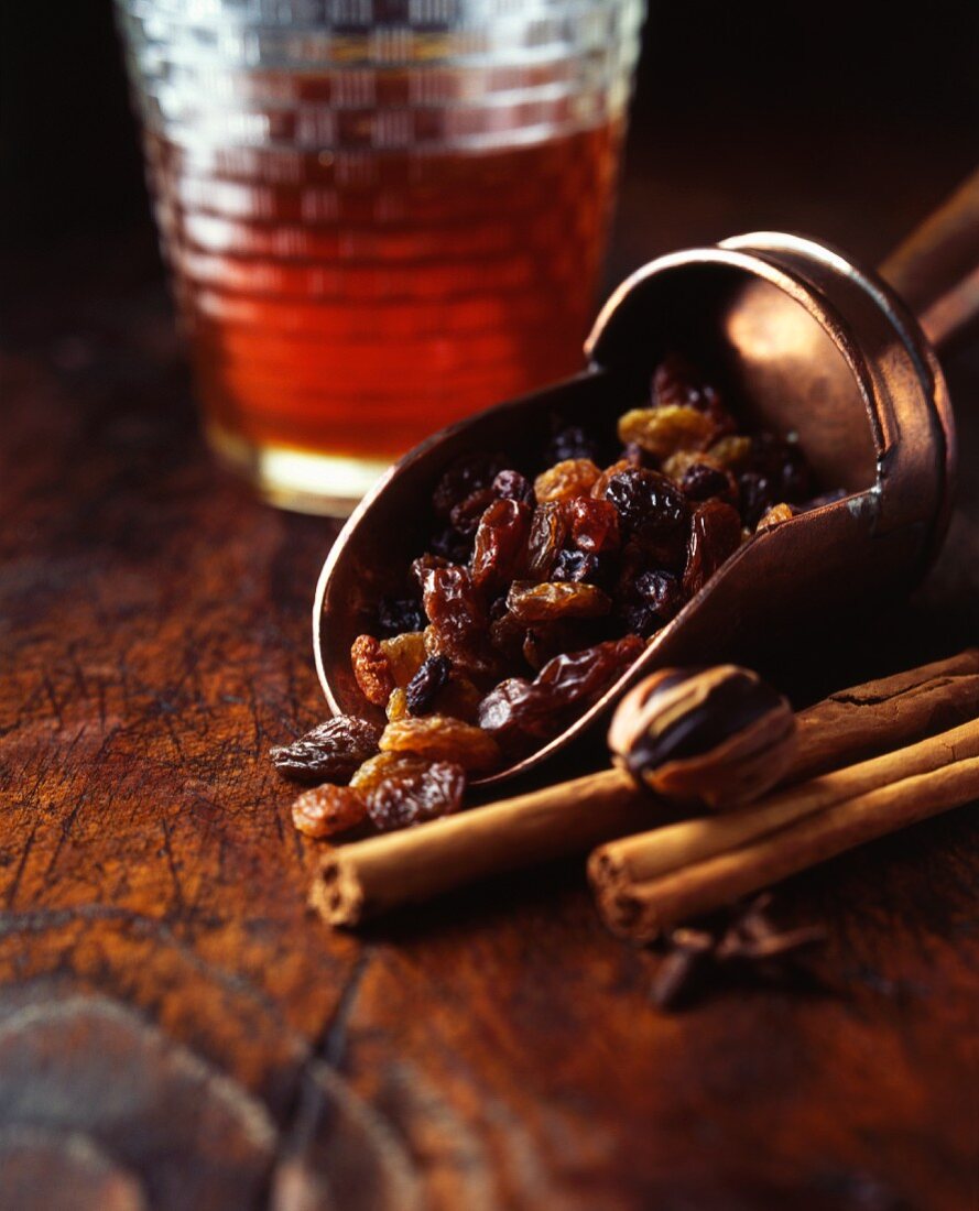 Mixed raisins in a scoop with cinnamon sticks and a glass of ale