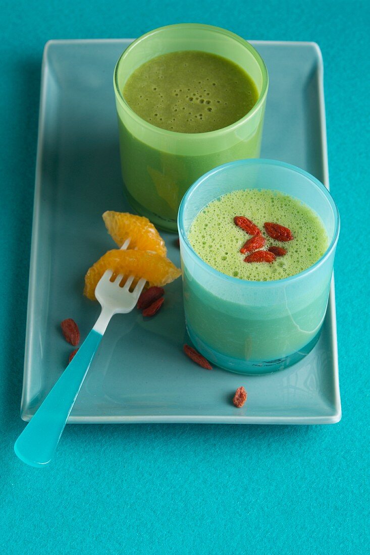 A green smoothie made with mandarin, and a banana and pineapple smoothie with goji berries