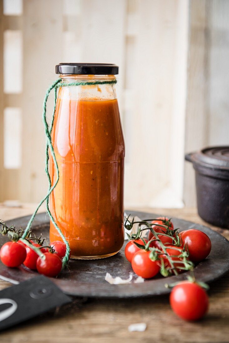 Eine Flasche hausgemachtes Ketchup mit Kirschtomaten