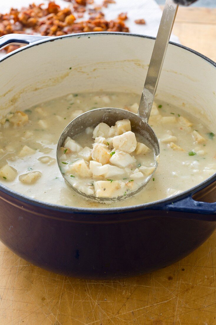 New England fish chowder in a soup pan with a ladle (USA)