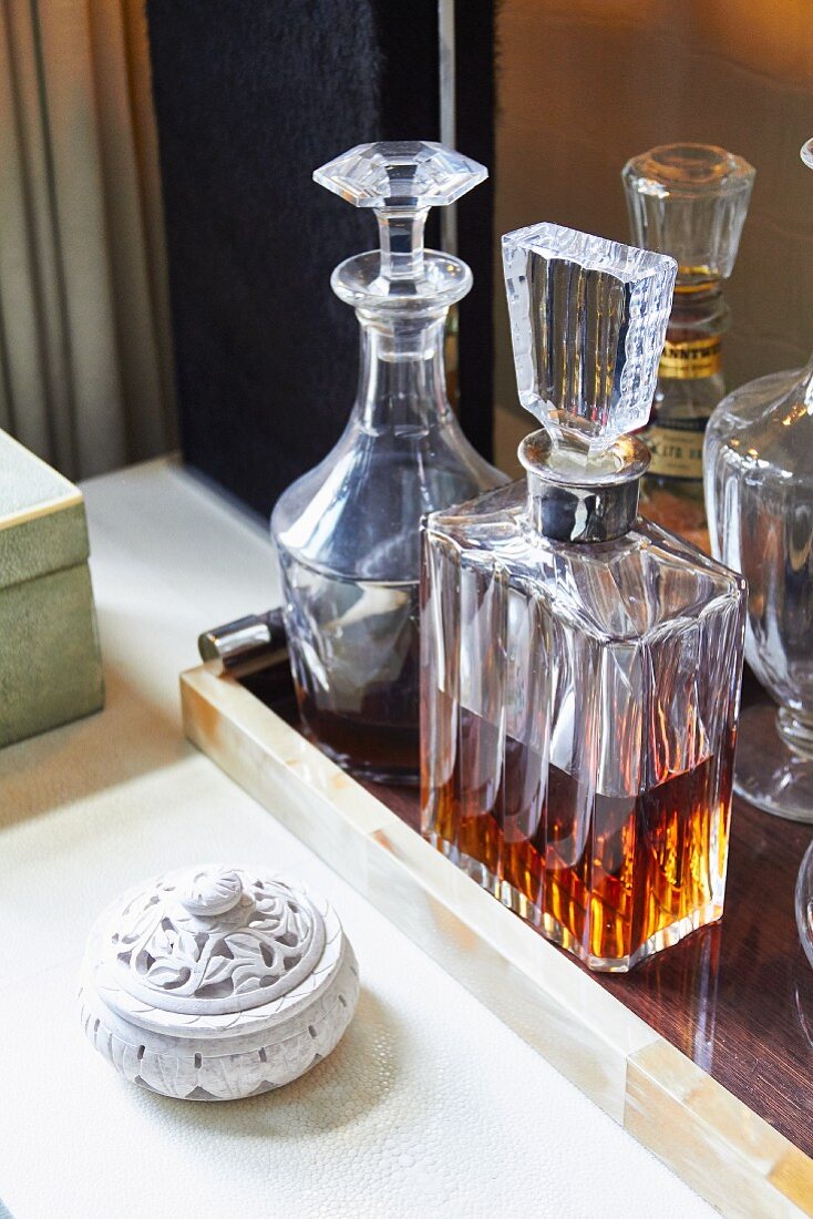 Elegant crystal carafes on tray next to hand-carved stone box