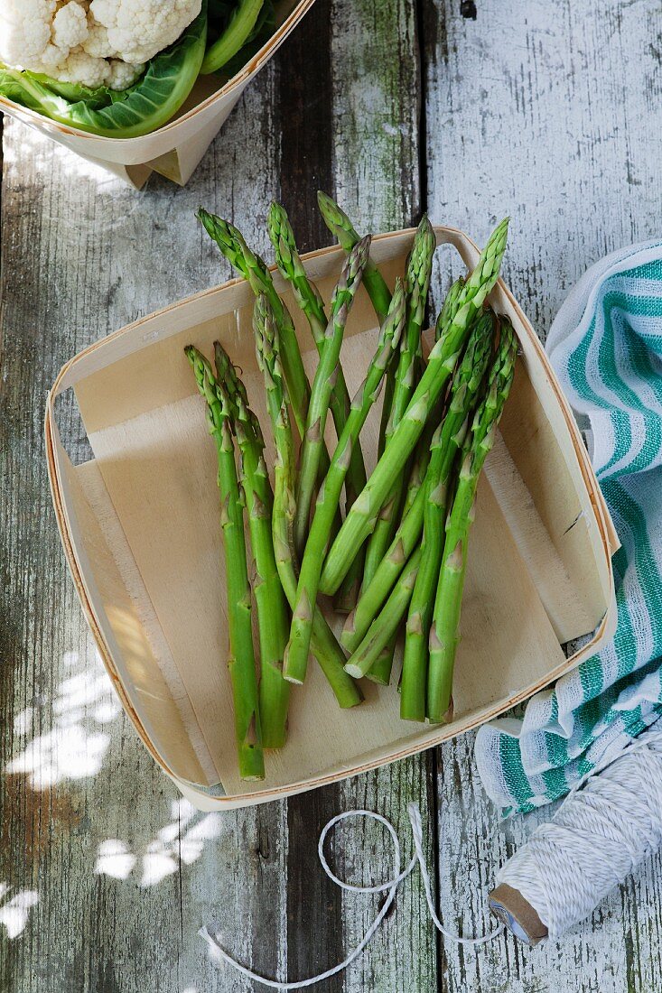 Green asparagus in a wooden basket on a wooden table