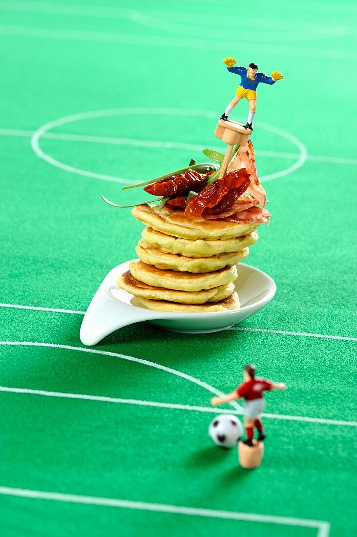 Pancakes with dried tomatoes and salami with a football decorations