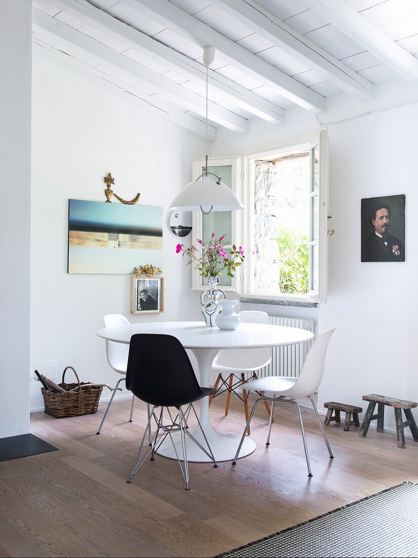 Classic chairs around white Tulip Table in corner dining area below open window