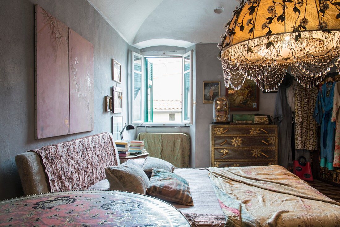 Bed with patterned headboard and lit, artistic lampshade in bedroom