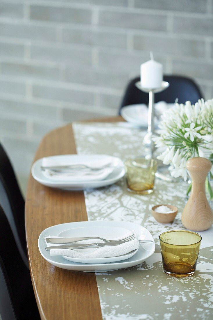 Gedeckter Tisch mit weißem Geschirr, Kerzenhalter und Blumenstrauss