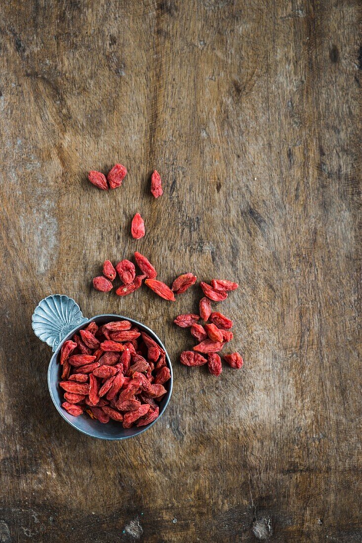 Dried goji berries in small bowls on a wooden background (top view)