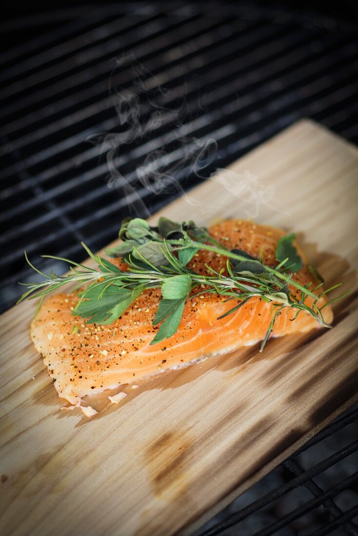 More salmon fed with herbs and spices on smoking board on a grill