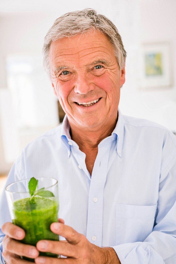 An older man holding a glass of green … – License Images – 11957204 ❘  StockFood