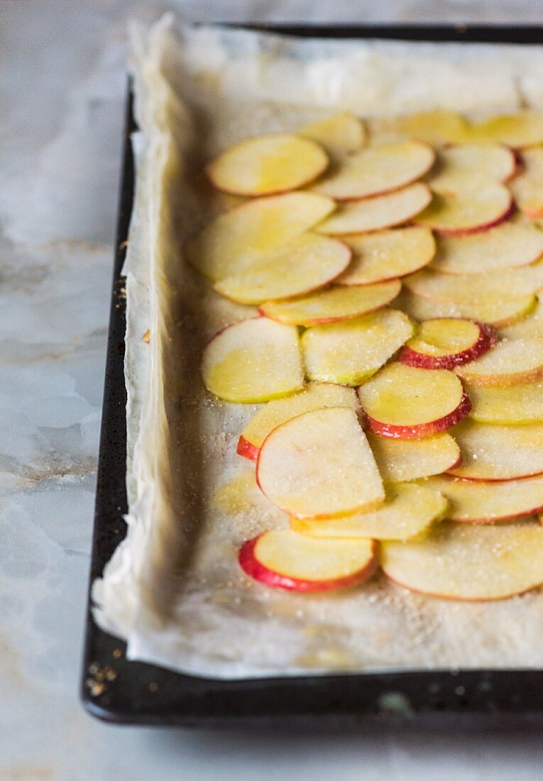 Filo pastry with apple slices on a baking tray (raw)