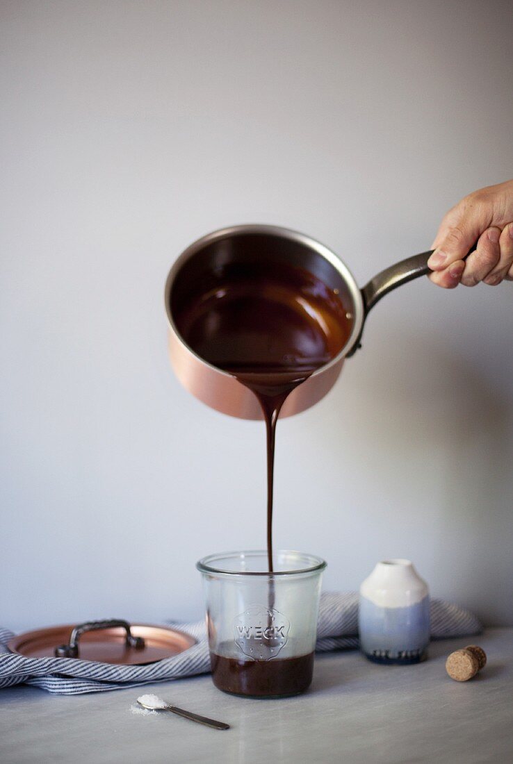 Salted chocolate fudge sauce being poured from a pan into a glass