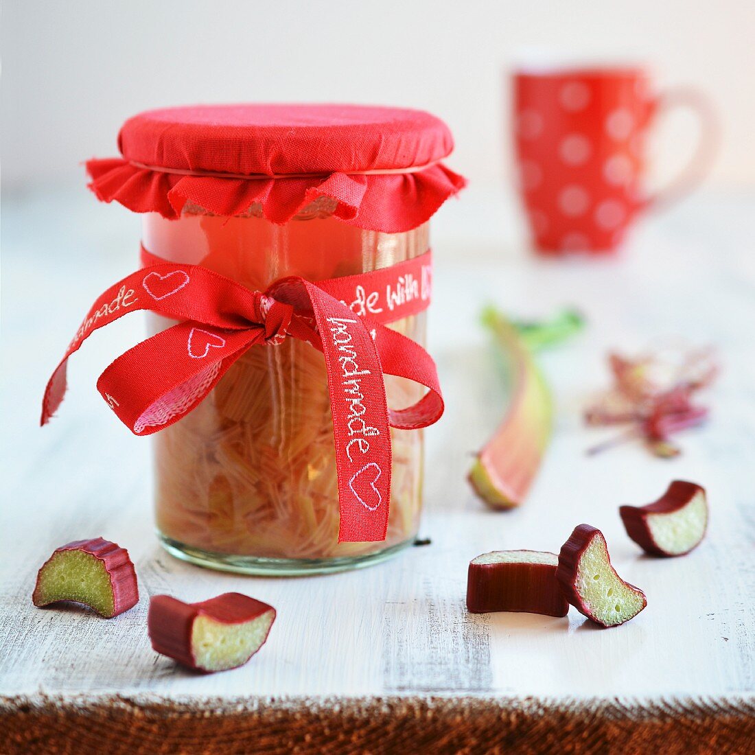 A jar of homemade rhubarb compote with a red bow