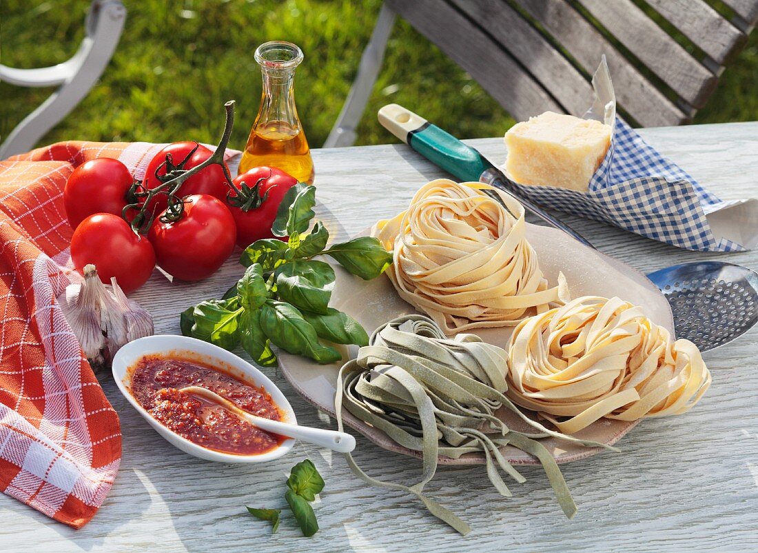 Bandnudeln, Tomatensauce und Zutaten auf Gartentisch