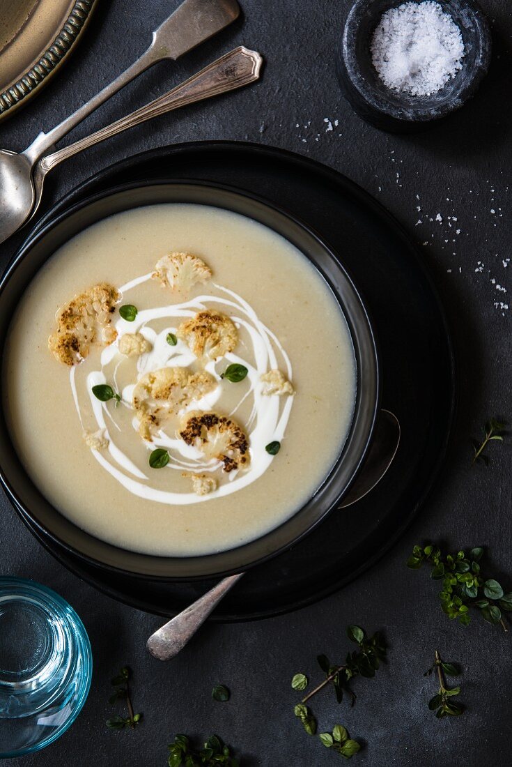 A bowl of cauliflower soup with cream and herbs