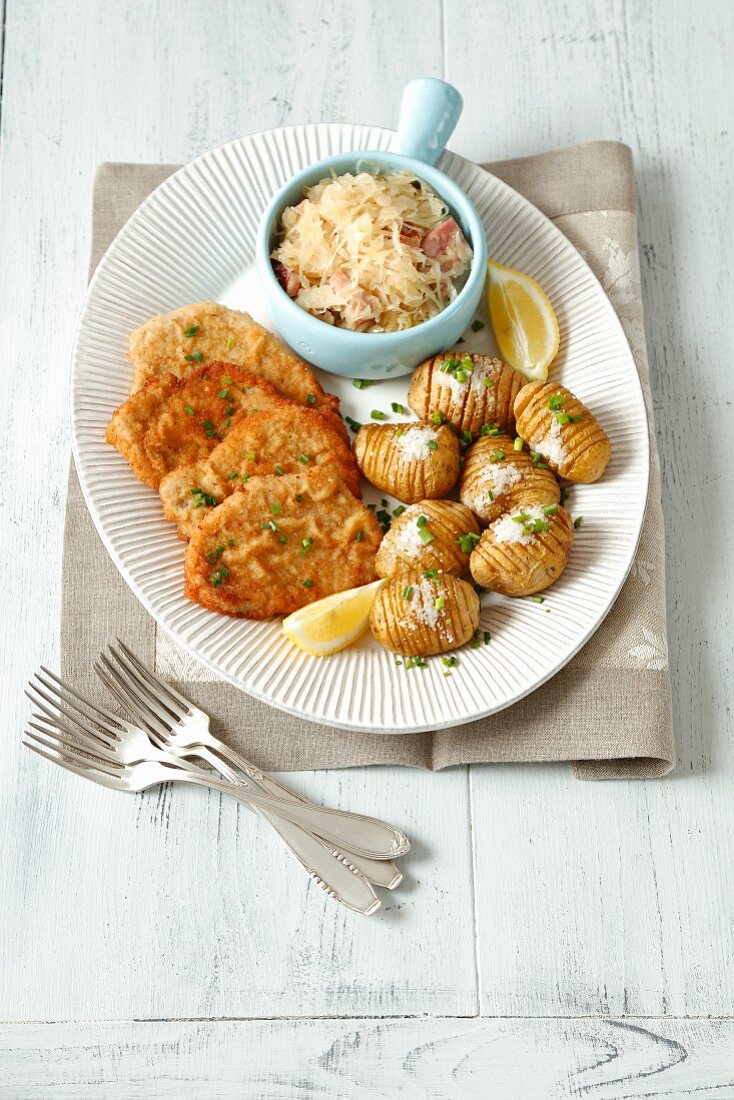 Panierte Schweineschnitzel mit Hasselback-Kartoffeln und Sauerkraut