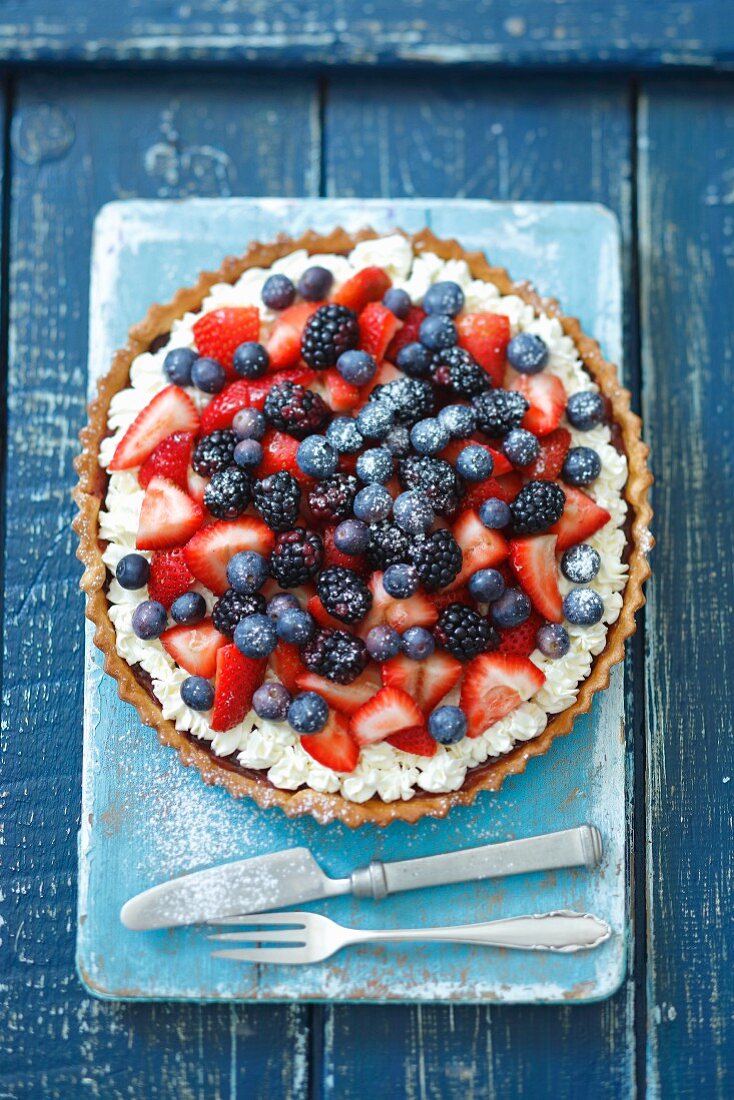 Berry tart with chocolate cream, strawberry jam, whipped cream and fresh berries