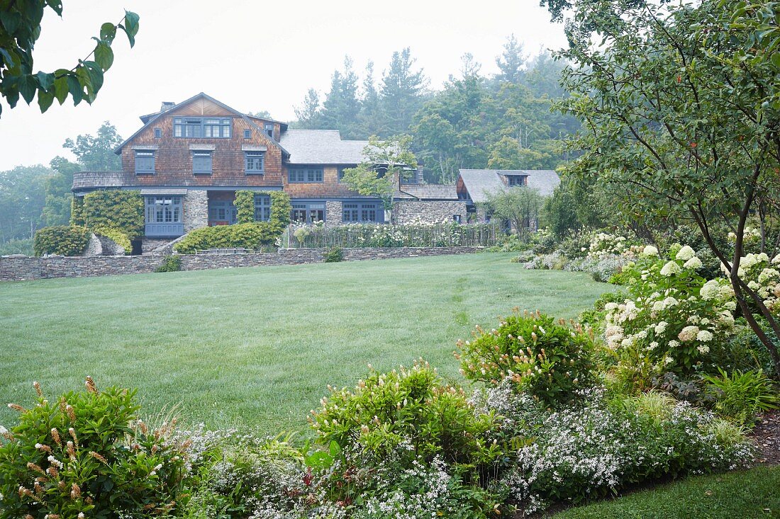 Weitläufiger Garten mit grosser Wiese, im Hintergrund altes Arts-and-Crafts-Schindel-Haus