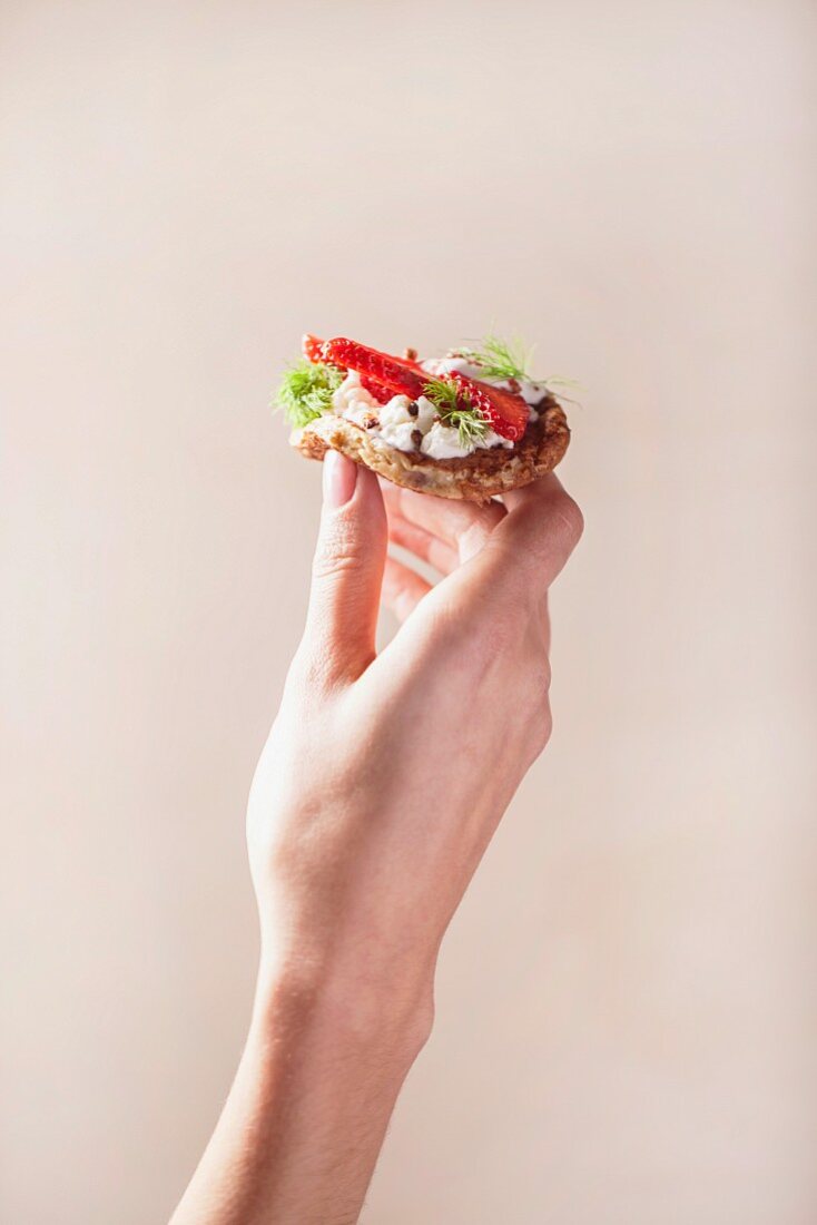 A mini pancake with cream cheese, pepper and strawberries