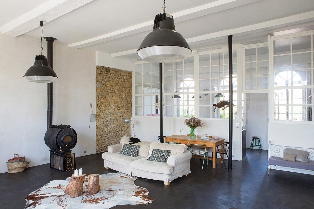 Animal-skin rug, tree stump tables and wood-burning stove in lounge area