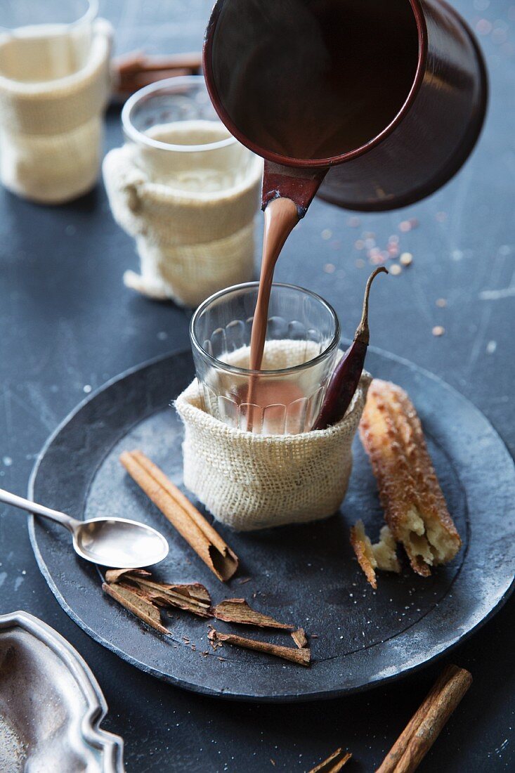 Hot chocolate with spices being poured into glasses