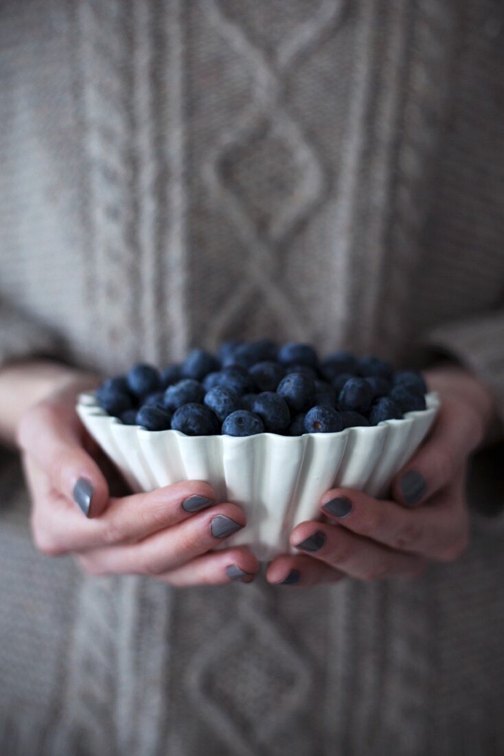 A woman holding a bowl of fresh blueberries