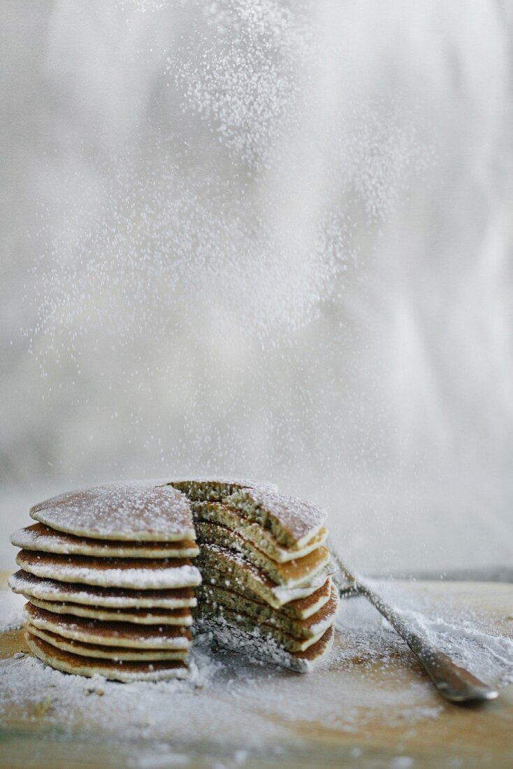 A stack of pancakes being dusted with dancing sugar