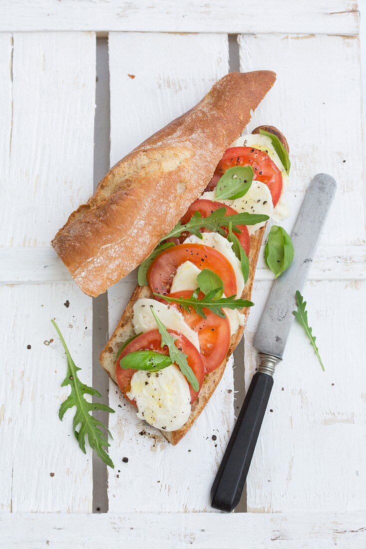 A sandwich with mozzarella, tomatoes, rocket and basil