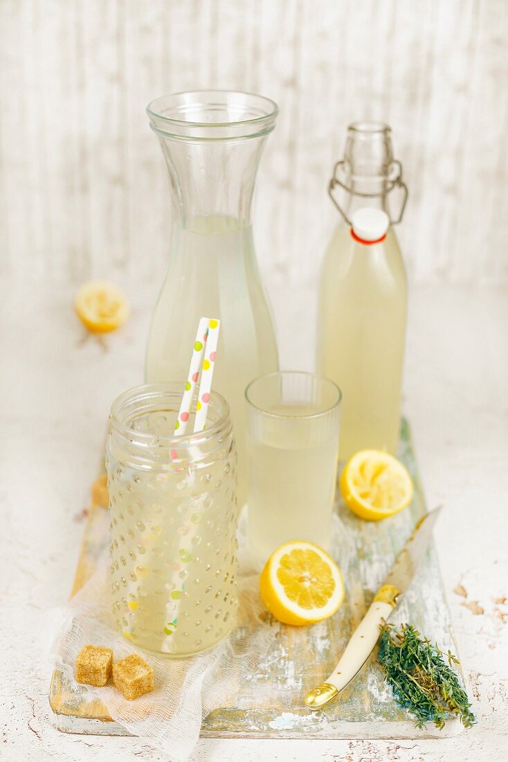 Thymian-Zitronenlimonade in Flasche, Karaffe und Gläsern