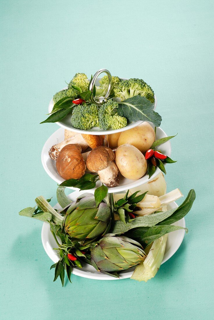 An arrangement of vegetables and mushrooms on a cake stand