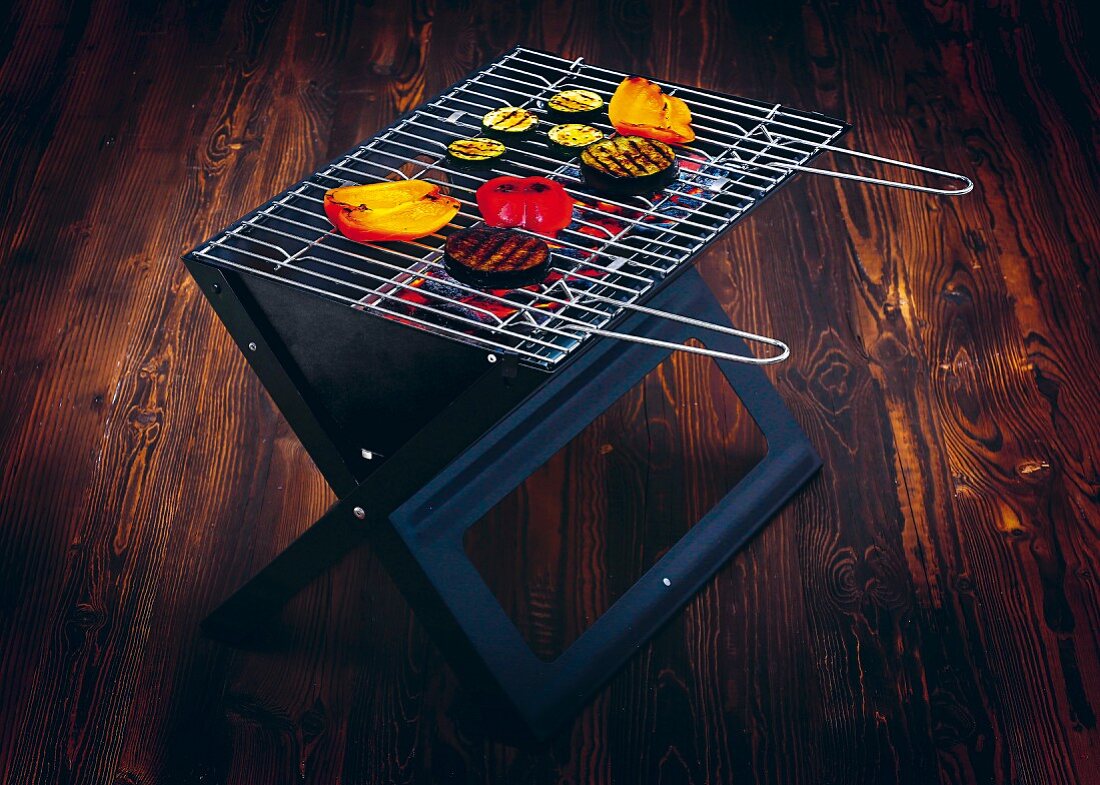 Food on a folding grill on a dark wooden surface