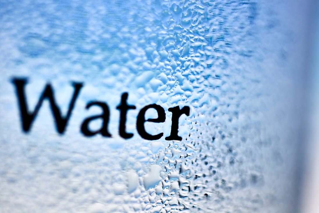 Condensation on a glass with the word 'water' (close-up)